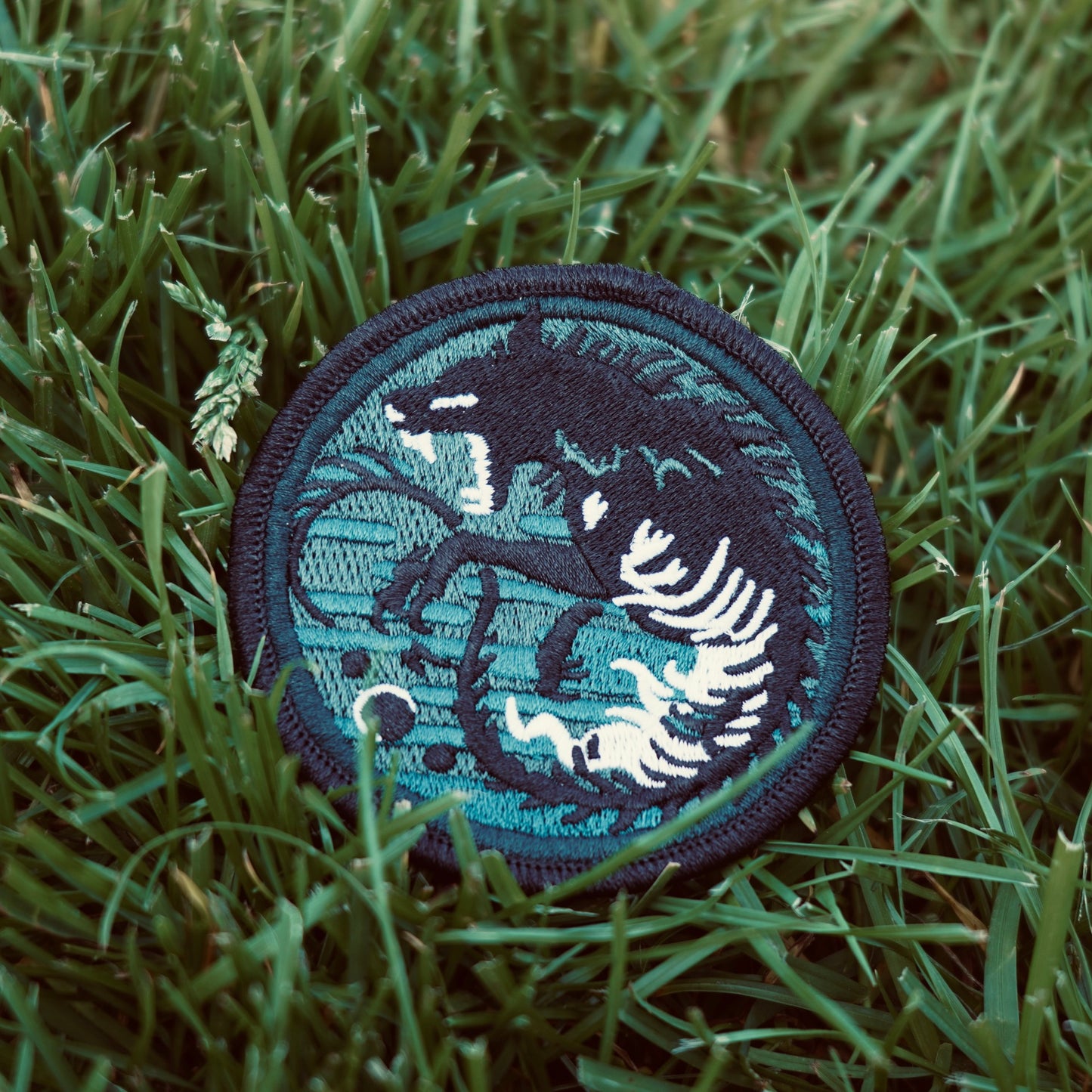 Embroidered patch of wolf chasing stages of the moon glow in the dark thread