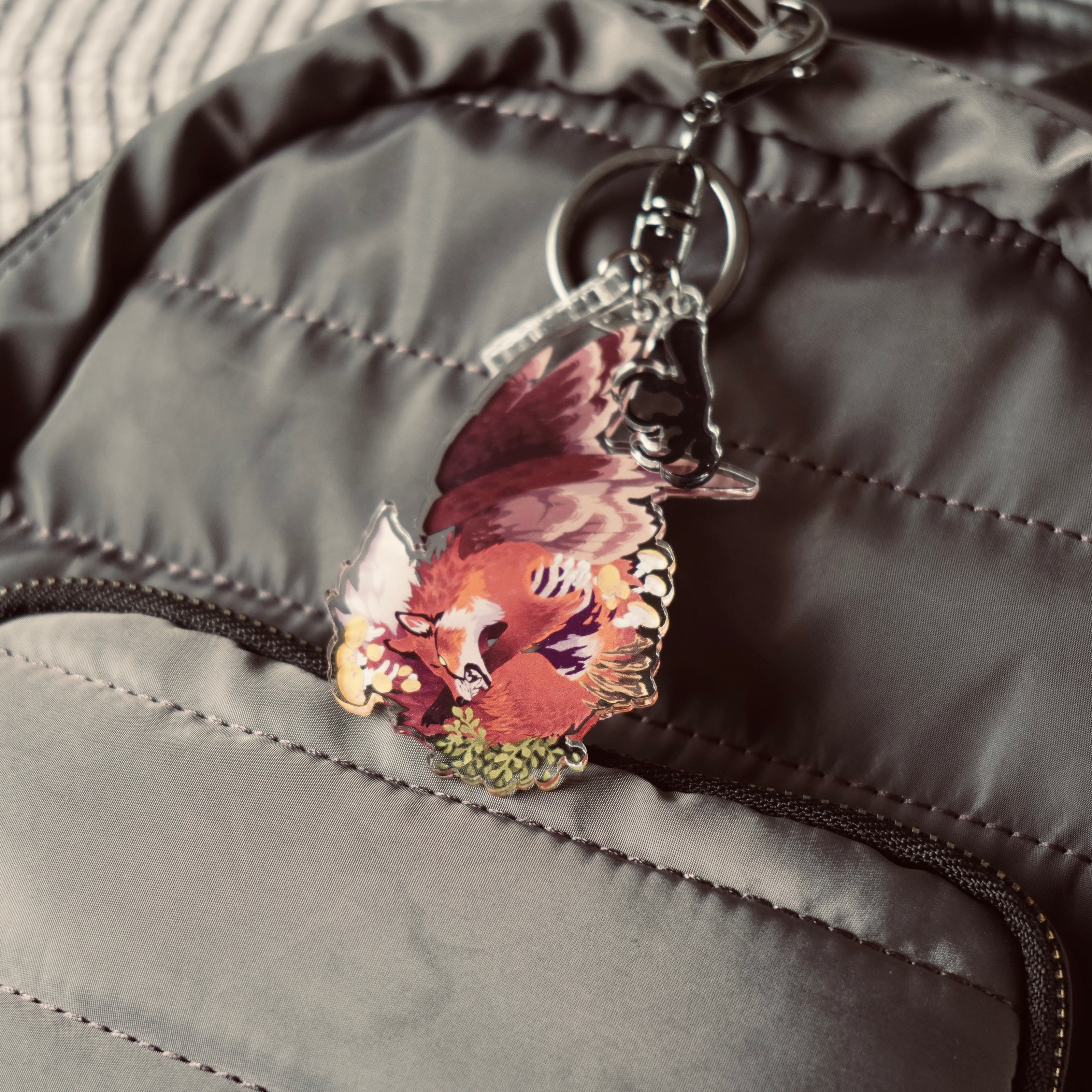 Keychain of acrylic charms, the main charm is of a dead fox growing wings and plants, blooming