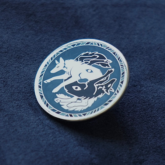 Circular emblem with a white and black wolves wolf design on a blue textured background enamel pin